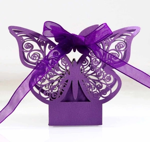 Close-up of laser-cut butterfly wedding favor box with purple ribbon and intricate texture