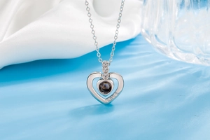Macro shot of silver heart projection pendant with LOVE engraving on a wavy blue surface