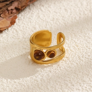 Close-up of golden wide open ring featuring inlaid brown tiger eye stones and matte finish