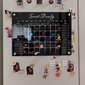 Close-up of black acrylic dry erase calendar board with magnetic markers for family schedule