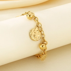Detail of 18K gold-plated bracelet with sun pendant and hammered textured charms