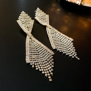 Detailed macro view of golden tassel earrings with geometric crystals on black leather