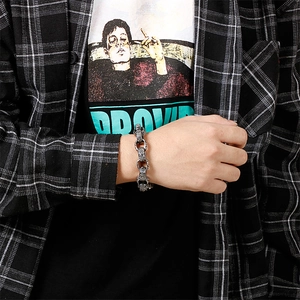 Macro detail of retro engraved stainless steel square Buddha head bracelet on a male wrist