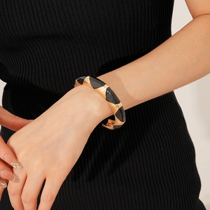Close-up of a French vintage oval open bangle featuring black oil drip on gold metal