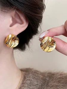 Detailed macro view of 18k gold plated pleated round stud earrings with unique texture