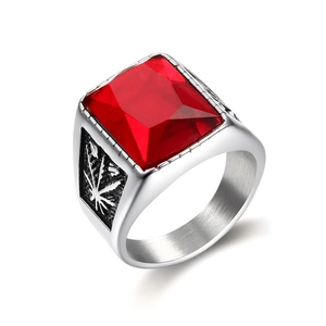 Macro detail of men's stainless steel ring with red gemstone and leaf pattern engravings