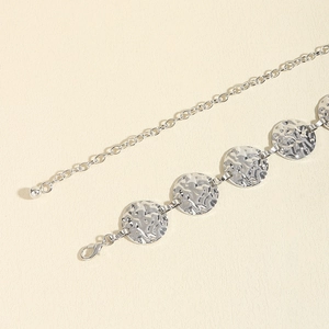 Detail of silver metal chain belt showing hammered texture rings and lobster clasp closure