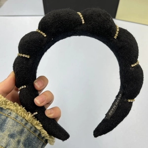 Close-up of black plush padded headband with golden rhinestone chains and handmade tag