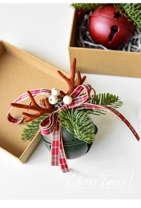 Detail of red and green metal Christmas bells with antlers and pine needles on a table