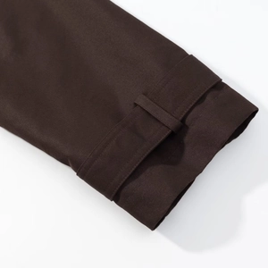 Detail of dark brown trench coat sleeve with sturdy twill fabric and adjustable buckle strap