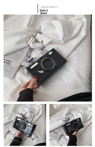 Macro shot of camera-shaped crossbody bag featuring silver chain and polka dot ribbon