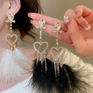 Detail of heart shaped rhinestone earrings with elegant feather tassels and bow accents