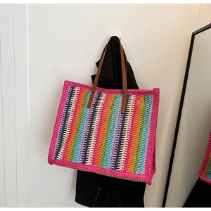 Detail of colorful striped woven tote bag with brown leather handles hanging on a wall