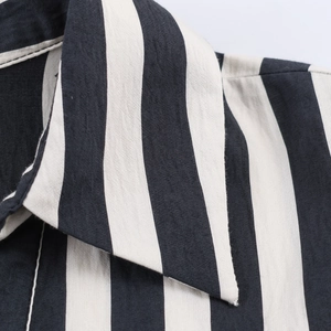 Detail close-up of the black and white striped shirt collar showing cotton linen texture