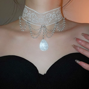 Gros plan sur un tour de cou en dentelle blanche avec franges de perles et pendentif goutte