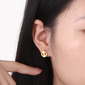 Close-up of a model wearing a gold anchor-shaped stud earring made of titanium steel