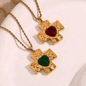 Detail of 18K gold plated cross necklace with twisted chain and heart-shaped gemstone