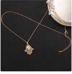 Detail of gold Hamsa Hand pendant with blue Evil Eye and multi-color rhinestones