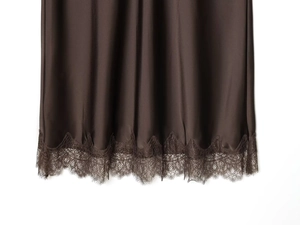 Détail de l'ourlet d'une jupe mi-longue en satin marron foncé avec dentelle