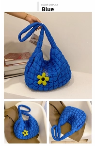 Detail of blue quilted cloud tote bag with bright yellow flower pendant and soft texture