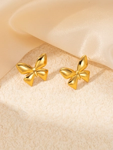 Close-up of golden butterfly stud earrings on premium textured stone and silk fabric