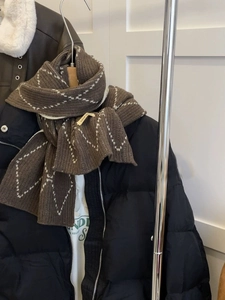 Detail of soft brown knit scarf with white diamond pattern and thick warm texture