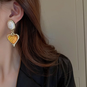 Vintage gold heart drop earrings with pleated resin and white oval stud worn by model