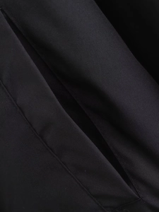 Detail shot of the black woven fabric texture and stitching of the reversible bomber jacket