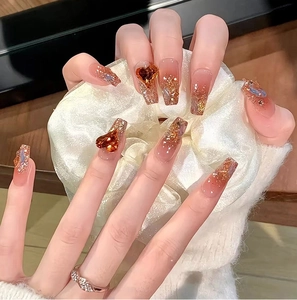 Detailed view of long coffin nails with amber glitter, aurora gradient and 3D heart gems