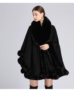Detail of black knit poncho with faux rabbit fur collar and fringed edge trim
