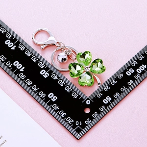 Green crystal clover keychain with silver metal rings measured on a ruler scale