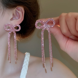 Close-up of pink bow tassel earrings with micro-set rhinestones on a female model