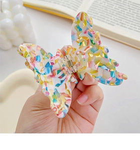 Detail of a butterfly hair claw clip with colorful marble pattern and metal spring
