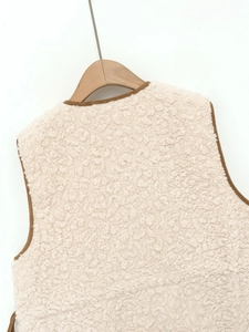 Detail of soft cream lamb wool vest with brown trim on the collar and armholes
