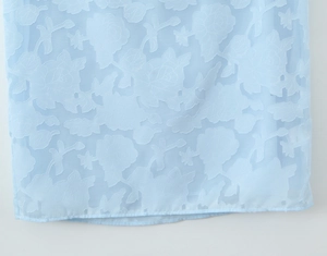 Détail du tissu en dentelle bleu clair avec broderie florale 3D sur l'ourlet de la robe