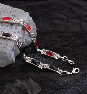 Macro detail of red and black crystals set in silver metal chain on dark stone