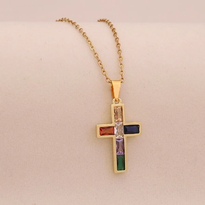 Macro shot of gold cross pendant necklace inlaid with multi-colored rectangle zirconias