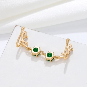 Detail of gold U-shaped nose clip with dual green emerald stones and fine chain link