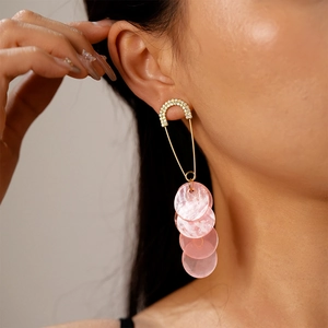 Detail of pink circular drop earrings with gold safety pin design and sparkling pavé crystals