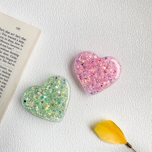 Detail of heart-shaped glitter phone grips with colorful sequins and resin finish