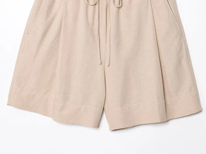 Detailed macro view of the beige linen blend fabric texture and stitching on casual shorts