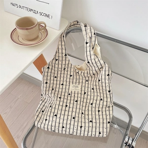 Detailed macro view of the beige canvas tote bag with black stripes and heart pattern