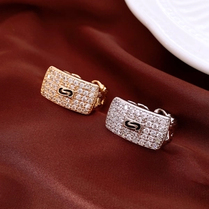 Detail of gold and silver rectangle chain rings with zircon pavé and S letter on satin