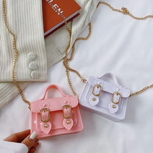 Mini jelly satchel bags in pink and white with gold chain straps on white fabric