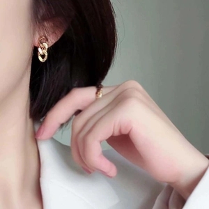 Elegant gold metal chain-link hoop earrings and matching ring set on a model