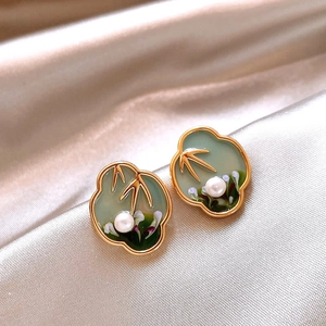 Détail de boucles d'oreilles vintage en émail avec motif bambou et perles sur soie