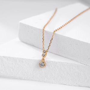 Detail of minimalist gold S925 sterling silver necklace with three zircon stones on stone stand