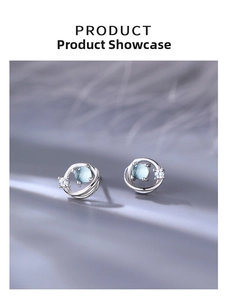 Detailed macro view of silver Saturn stud earrings with blue glass and cosmic stars