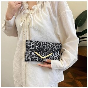 Detail of leopard print crossbody bag featuring a gold V-shaped clasp and metal chain strap