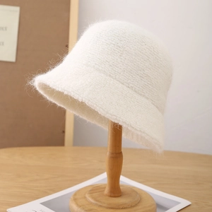 Gros plan détaillé d'un chapeau bob en laine blanche pelucheuse sur un support en bois